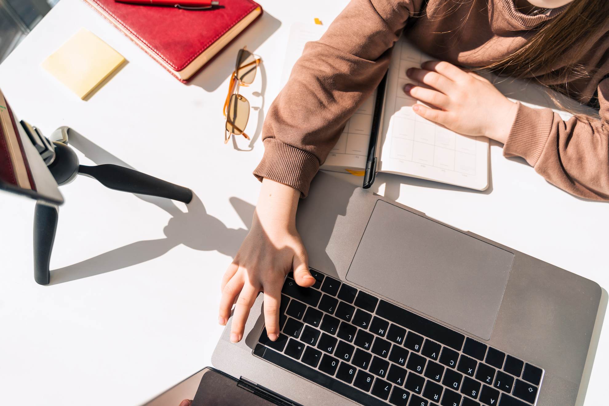 A woman working remotely from her mobile phone and laptop under the e-trader licence in Dubai.
