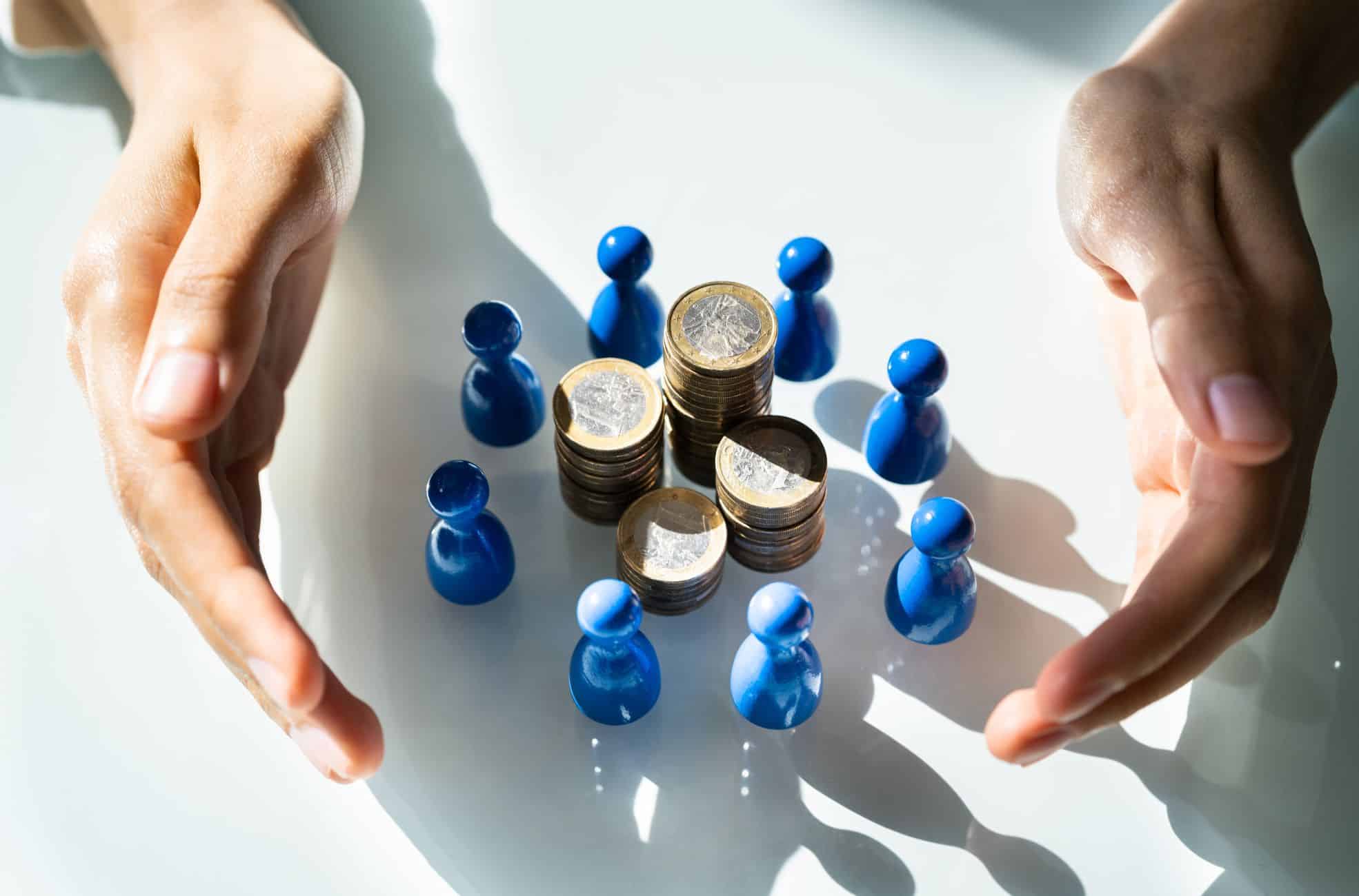 Hands Holding Pawns Around Money Showing Crowdfunding