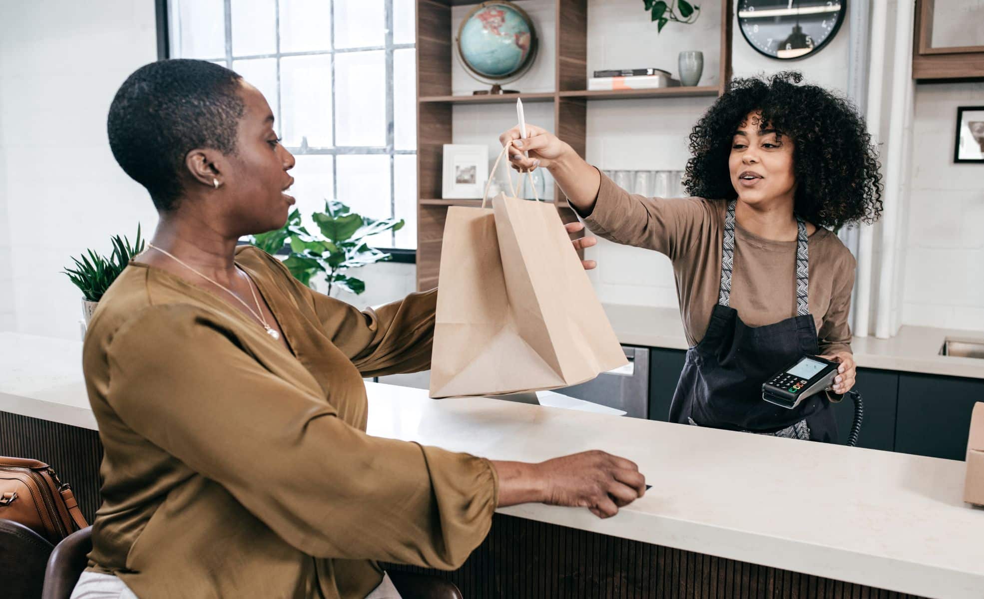Woman In Retail Handing Bag To Customer