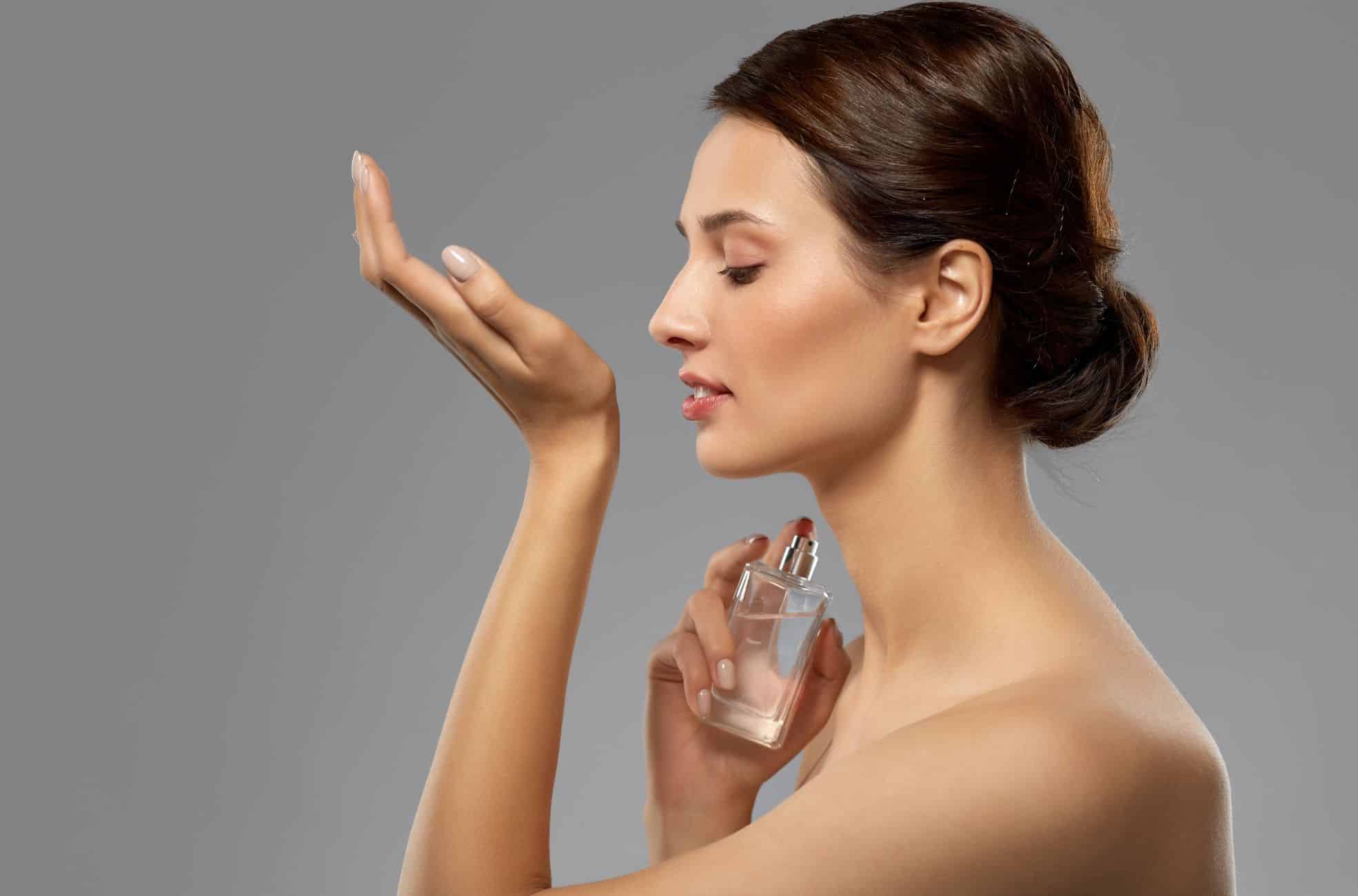 Woman Holding Perfume And Smelling Wrist