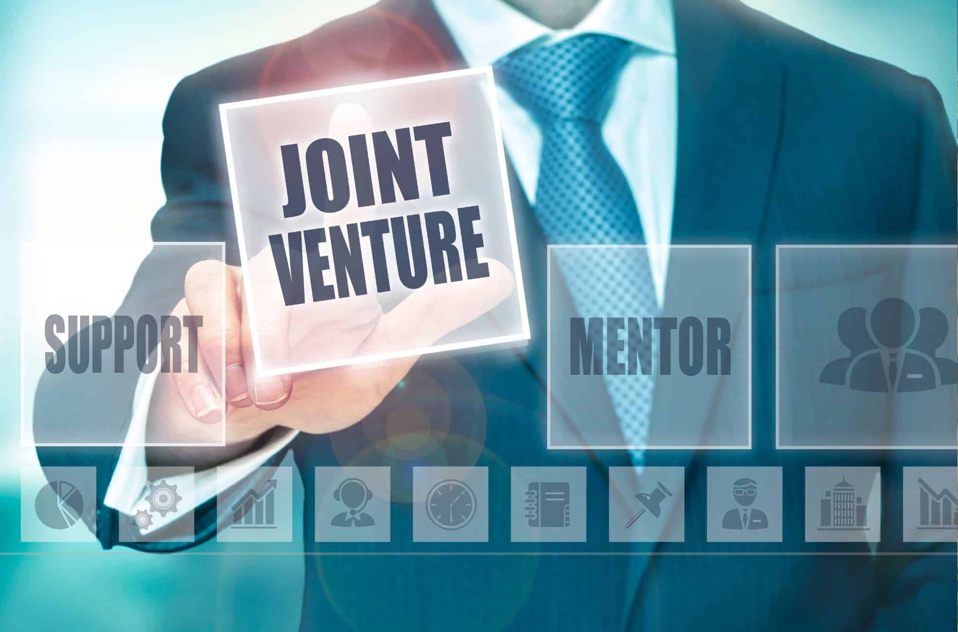 Businessman Pointing To Sign Saying "Joint Venture"