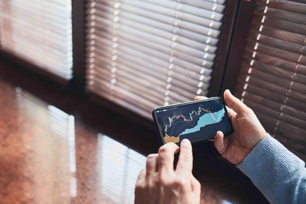 Person investing and trading stock on smartphone