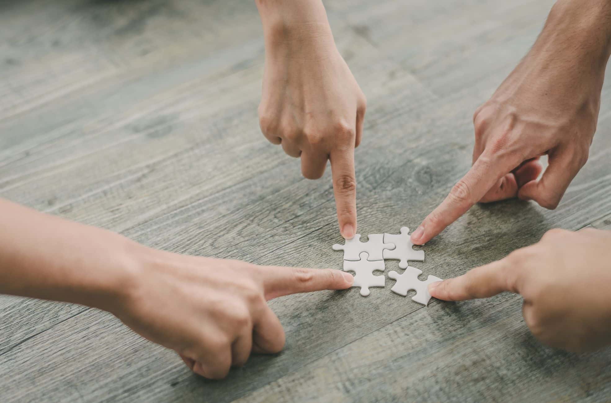 People Solving Pieces Of A Puzzle